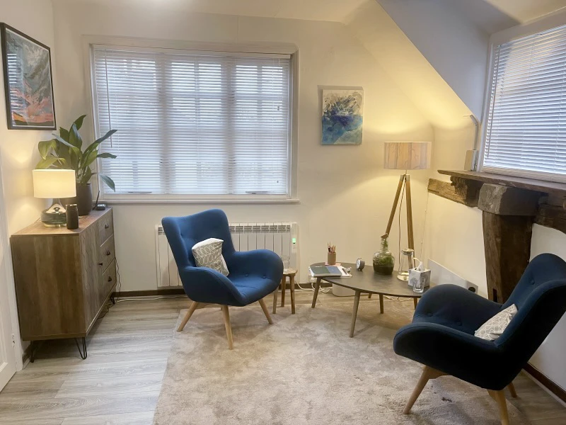 Alt Text Calm and welcoming EMDR therapy room with blue chairs, soft lighting and a comfortable counselling space